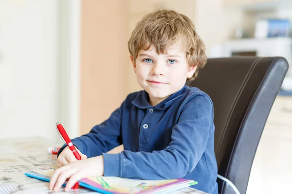 Menino pré-escolar em casa fazendo lição de casa escrevendo cartas com canetas coloridas — Fotografia de Stock