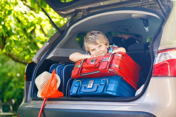 Kleiner Junge sitzt im Kofferraum des Autos, kurz bevor er in den Urlaub fährt — Stockfoto