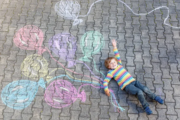 Junge hat Spaß mit bunten Luftballons, die mit Kreide gezeichnet werden — Stockfoto