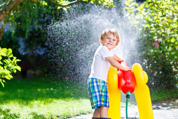 Menino brincando com um aspersor de água de mangueira de jardim — Fotografia de Stock