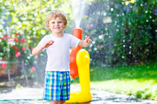 Menino brincando com um aspersor de água de mangueira de jardim — Fotografia de Stock