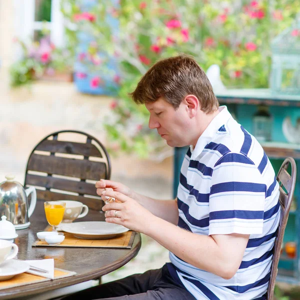 Jeune homme prenant le petit déjeuner dehors en été avec diverses confitures , — Photo