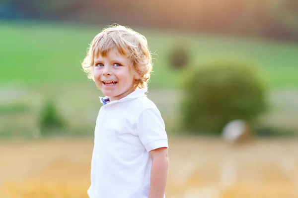 Szczęśliwe dziecko blond chłopiec, podziwiając zachód słońca w polu pszenicy. — Zdjęcie stockowe