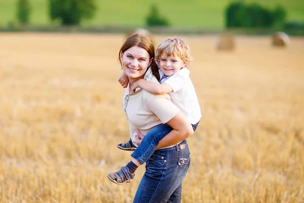 Mother holding kid boy on arms on wheat field in summer — Stock Photo, Image