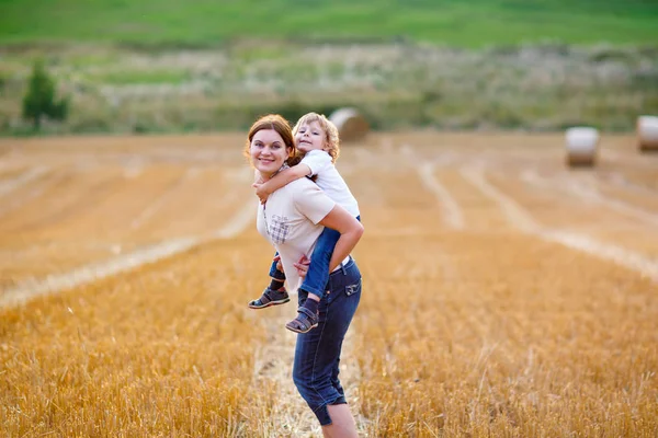 Mother holding kid boy on arms on wheat field in summer — Stock Photo, Image