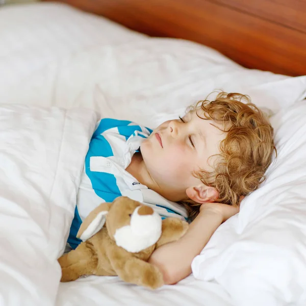 金发碧眼的小孩睡在他床上的玩具. — 图库照片
