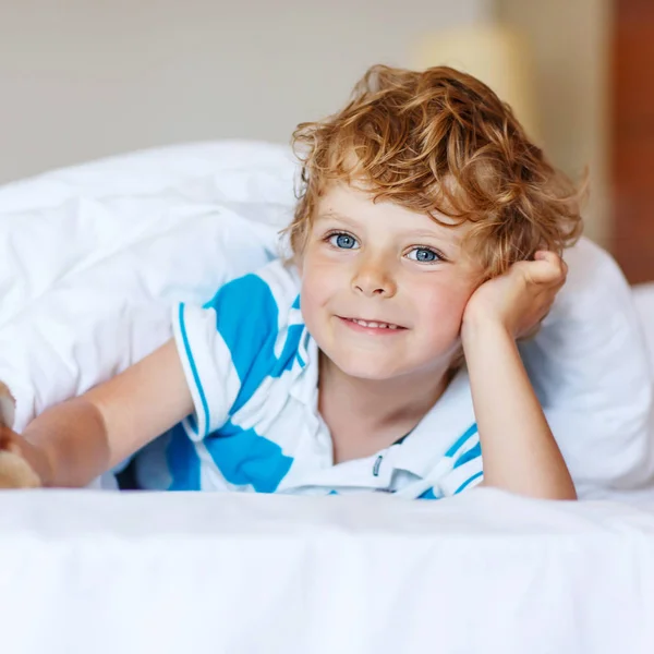 Adorable kid boy after sleeping in his white bed with toy — Stock Photo, Image