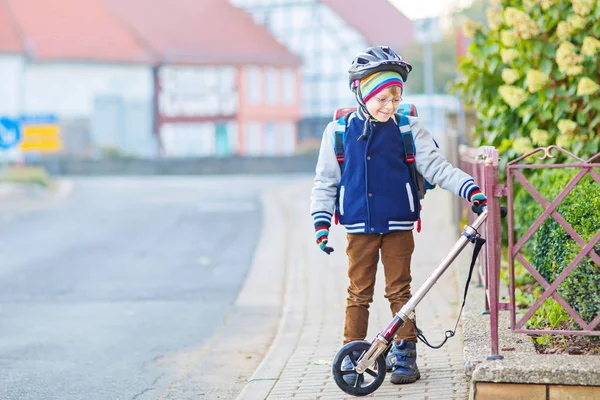 Kasklı küçük çocuk şehirde scooterıyla geziyor. — Stok fotoğraf