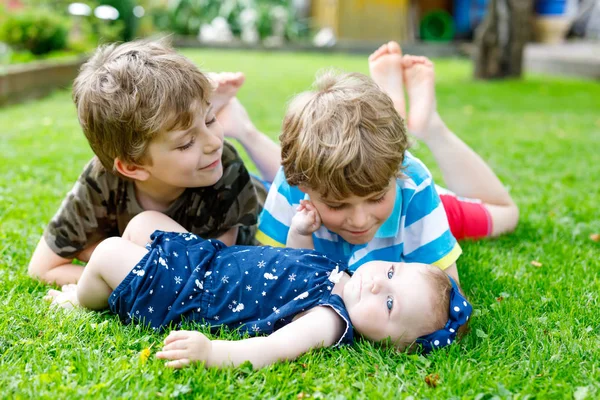 Zwei kleine glückliche Jungen mit neugeborenen Mädchen, süße Schwester. — Stockfoto