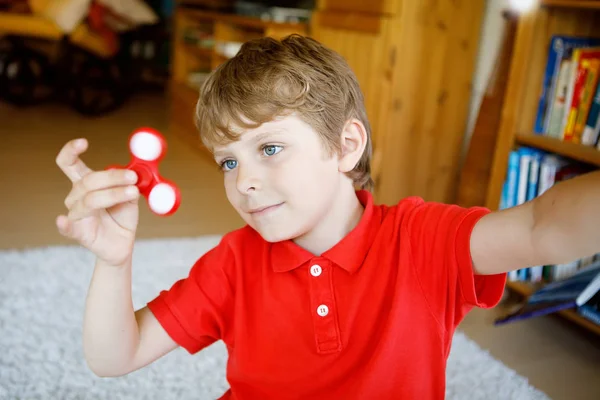 Niño de la escuela jugando con Tri Fidget Hand Spinner en interiores —  Fotos de Stock