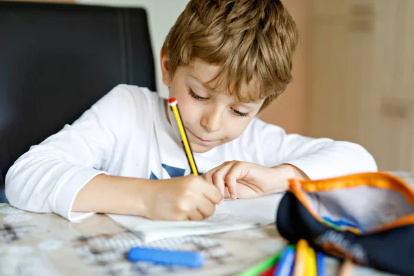 家庭で疲れている子供の少年は、カラフルなペンで文字を書く宿題を作る — ストック写真