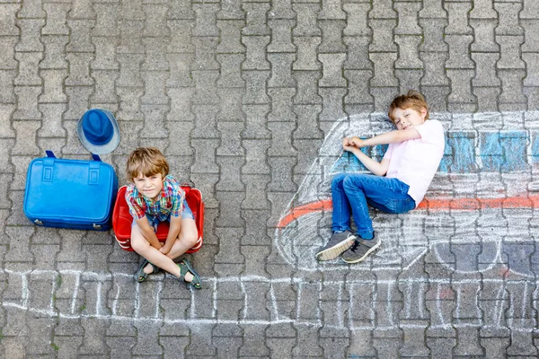 Dos niños pequeños se divierten con el dibujo de la imagen del tren con tiza de colores en el suelo — Foto de Stock