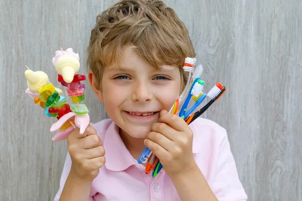 Little kid boy holding marshmallow skewer in one hand and toothbrushes in another — Stock Photo, Image
