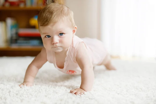 Klein grappig baby meisje tillen lichaam en leren kruipen. — Stockfoto