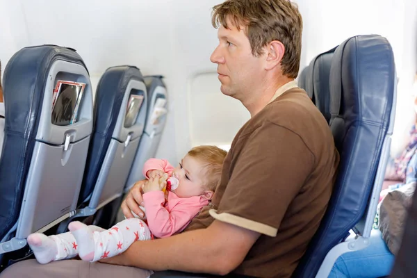 Jonge moe vader dragen zijn baby dochter tijdens vlucht op vliegtuig. — Stockfoto