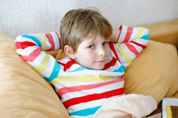 Little blonde school kid boy with glasses reading a book at home — Stock Photo, Image