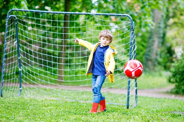 Ativo bonito menino jogando futebol e futebol e se divertindo — Fotografia de Stock