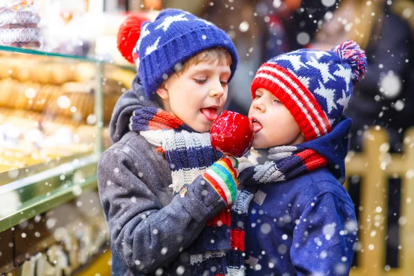 Deux petits garçons mangeant des bonbons à la pomme au marché de Noël — Photo