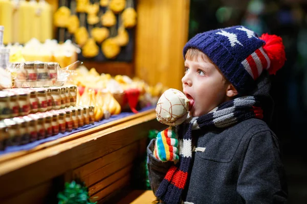 Menino comendo açúcar doce de maçã stand no mercado de Natal — Fotografia de Stock