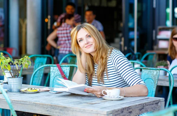 Mujer bebiendo café y leyendo libro en la cafetería —  Fotos de Stock