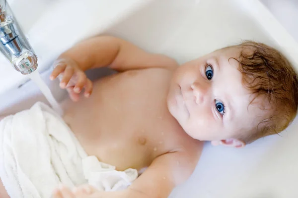 Schattige schattig baby nemen bad in wassen gootsteen en waterkraan pak. — Stockfoto