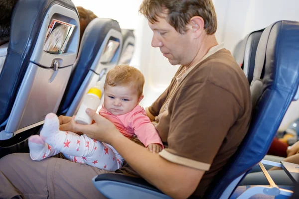 Jonge moe vader en dochter met huilende baby tijdens vlucht op vliegtuig op vakantie te gaan — Stockfoto
