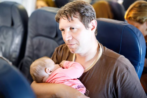 Молодой уставший отец и его спящая маленькая дочь во время полета на самолете собирается в отпуск — стоковое фото