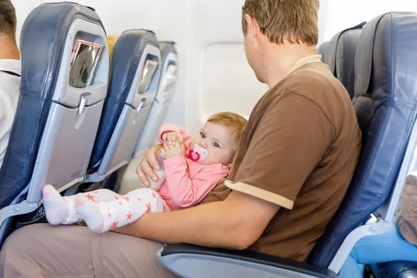 Joven padre cansado llevar a su hija bebé durante el vuelo en avión . — Foto de Stock