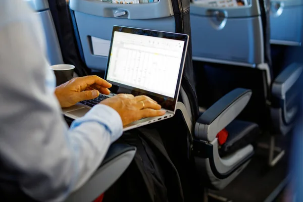 Giovane uomo d'affari irriconoscibile con taccuino seduto all'interno di un aereo — Foto Stock
