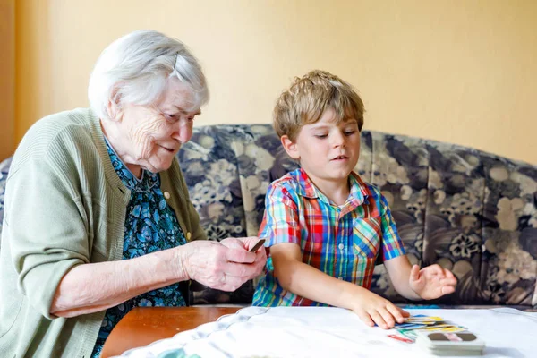 Active little preschool kid boy and grand grandmother playing card game together at home — Stock Photo, Image