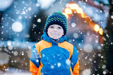 Mutlu çocuk kışın karla eğleniyor.