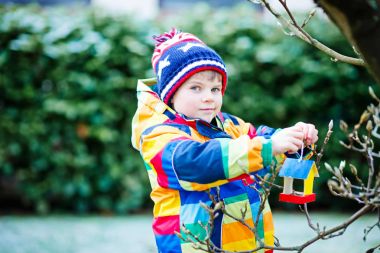Küçük çocuk çocuk kuş evi kış aylarında beslenme için ağaç üzerinde asılı