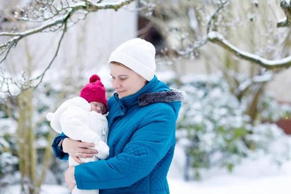 Mother holding newborn baby girl on arm outdoors