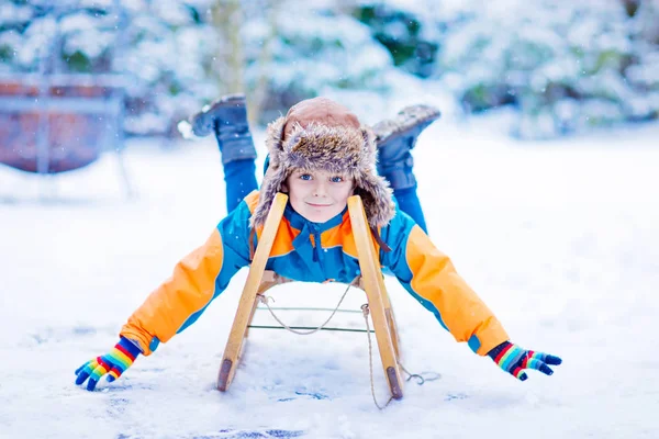 Маленький мальчик наслаждается катанием на санях зимой — стоковое фото