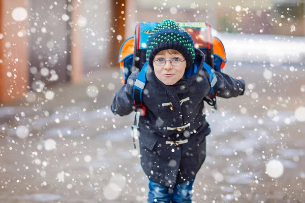 Menino feliz se divertindo com neve a caminho da escola — Fotografia de Stock