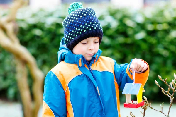 Niño colgando casa de pájaros en el árbol para alimentarse en invierno —  Fotos de Stock