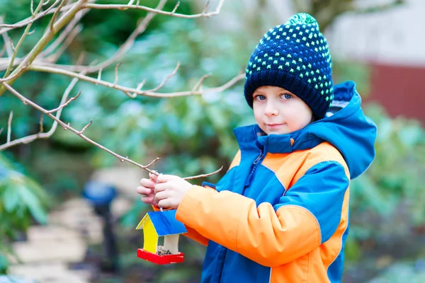 Ragazzino appeso casa uccello sull'albero per l'alimentazione in inverno — Foto Stock