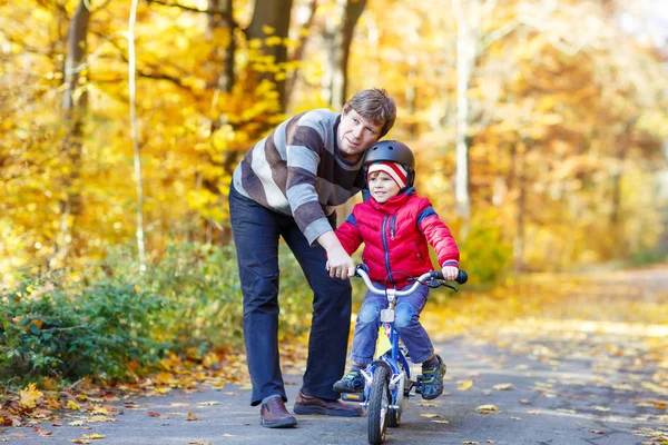 Маленький мальчик и отец с велосипедом в осеннем лесу — стоковое фото