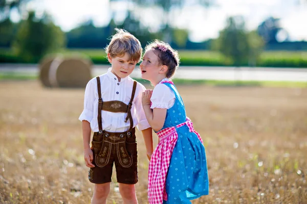 Two kids, boy and girl in traditional Bavarian costumes in wheat field — Stock Photo, Image