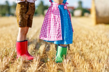 İki çocuk geleneksel Bavyera kostümleri ve kırmızı ve yeşil lastik çizmeler buğday alanında