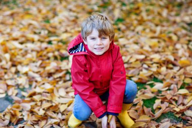 mutlu sevimli küçük çocuk çocuk bahçesinde oynarken sonbahar yaprakları ile