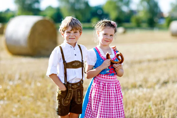 Dvě děti, chlapec a dívka v tradičních bavorských kostýmech v pšeničném poli — Stock fotografie