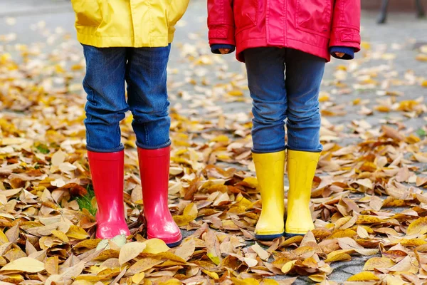 Zbliżenie dzieci nogi w gumowe buty, taniec i idąc przez jesienią liści — Zdjęcie stockowe