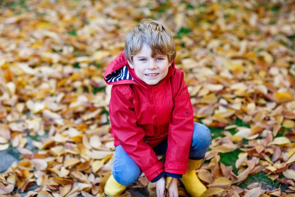 mutlu sevimli küçük çocuk çocuk bahçesinde oynarken sonbahar yaprakları ile