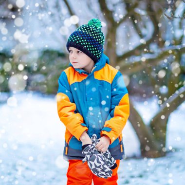 Mutlu çocuk kışın karla eğleniyor.