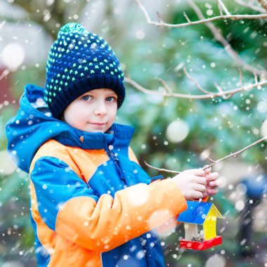 Küçük çocuk çocuk kuş evi kış aylarında beslenme için ağaç üzerinde asılı