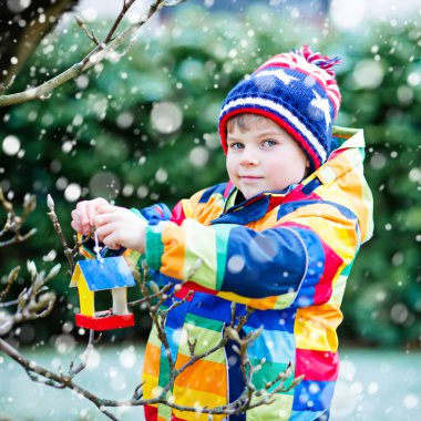 Küçük çocuk çocuk kuş evi kış aylarında beslenme için ağaç üzerinde asılı