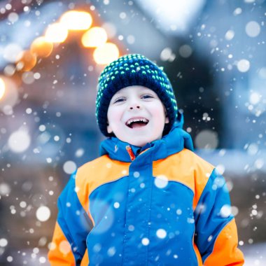 Mutlu çocuk kışın karla eğleniyor.