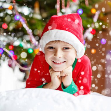 Noel ağacı ve ba ışıkları ile Noel Baba şapkalı küçük çocuk çocuk