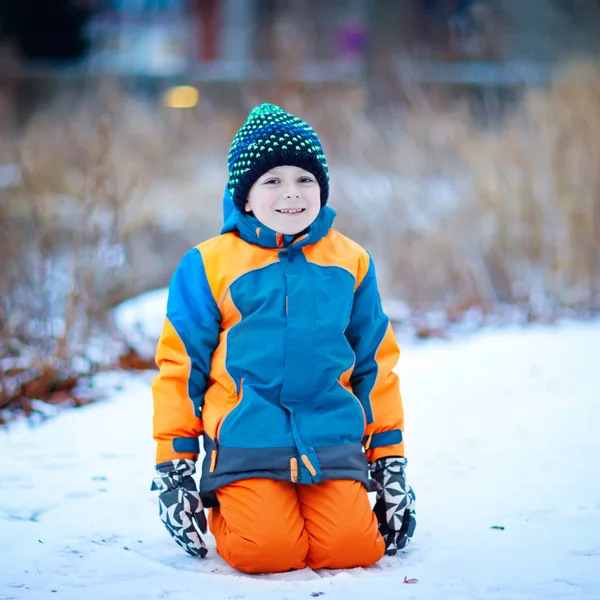 Mutlu çocuk kışın karla eğleniyor.